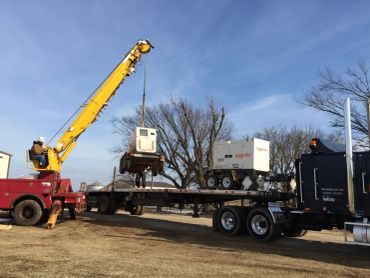 Crane loading equipment onto a flatbed truck.