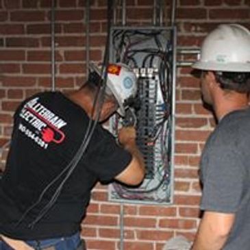 Electricians working on an electrical panel.