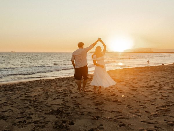 Couple dancing on the beach at sunset.