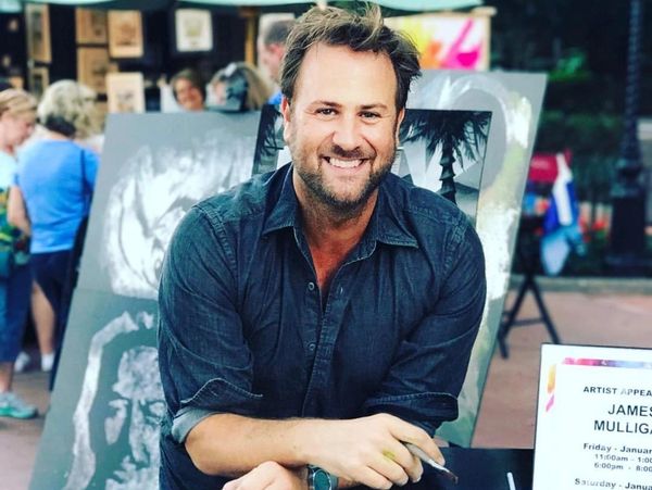Smiling man at outdoor art event.