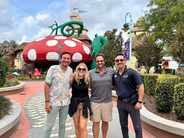 Group of four people posing in front of a giant mushroom attraction.