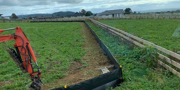Excavator working on farmland with new fencing.