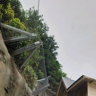 Protective fence on a rocky slope with greenery.