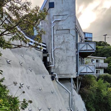 House built on steep slope with metal balconies.