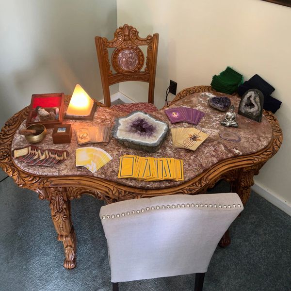 An elegant wood and marble table setup for a psychic reading with amethysts and tarot cards.