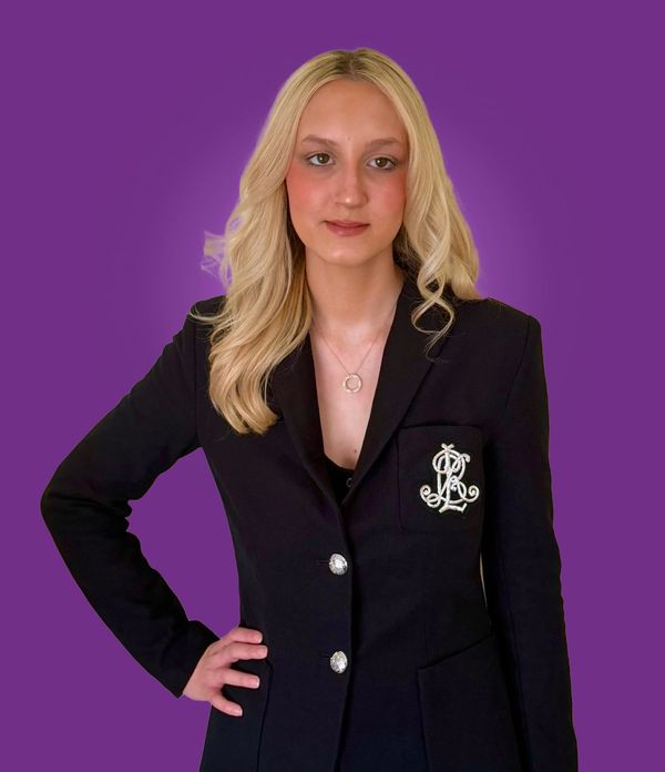 A beautiful young woman with long blonde hair and a slight smile wearing a black business suit.