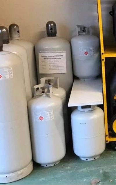 Several white propane tanks stored indoors near shelving.