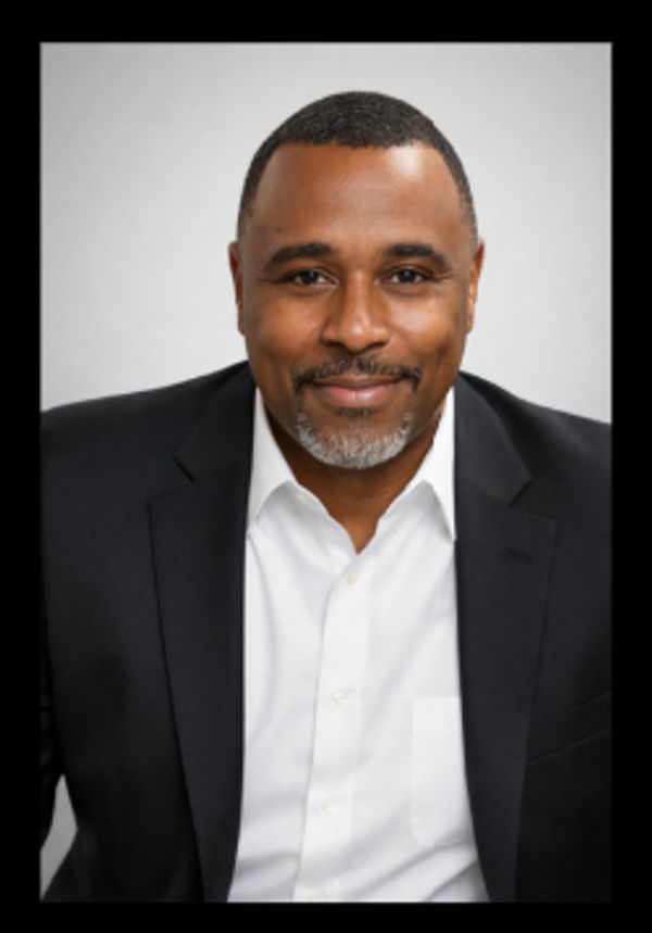 Confident man in a black suit and white shirt smiling.