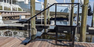 Metal dock stairs with handrails leading down to water at a marina.