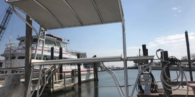 Boat lift docked at a marina with a boat in the background.
