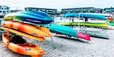 Colorful kayaks stacked on racks near waterfront homes.