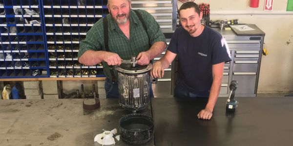 Two men working on a motor in a workshop.