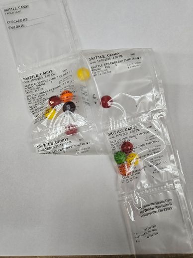 Packets of Skittle candy with detailed labels on white background.