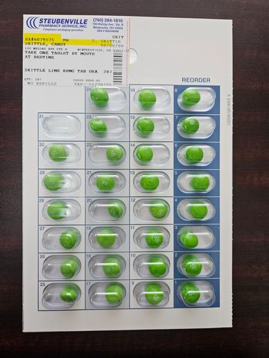 A blister pack with green and white capsules on a dark surface.