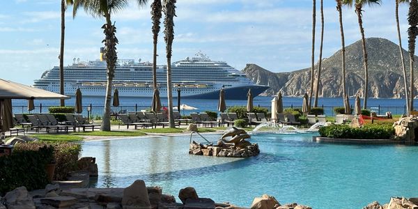 Cruise ship on the ocean near rocky hills, with a pool, lounge chairs