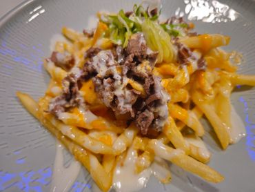 Fries topped with meat, cheese sauce, and garnished with greens.