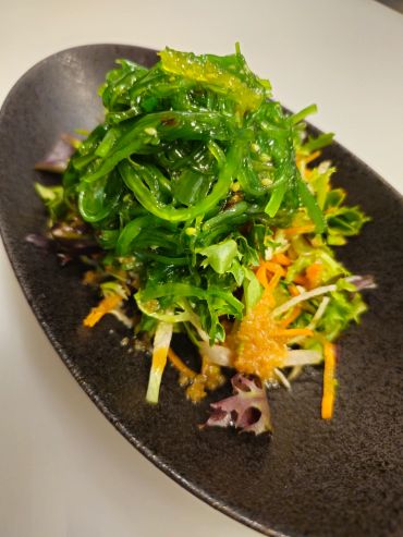 Fresh seaweed salad on a black plate.