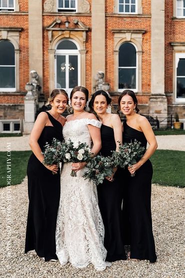 Bride and bridesmaids posing outside a historic building.