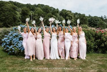Bridesmaids and bride joyfully posing with bouquets outdoors.