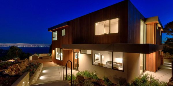 Modern house illuminated at night with city view.