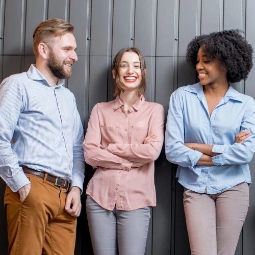 three people standing up against a wall smiling