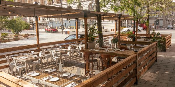 Terrasse de restaurant en bois avec tables dressées.