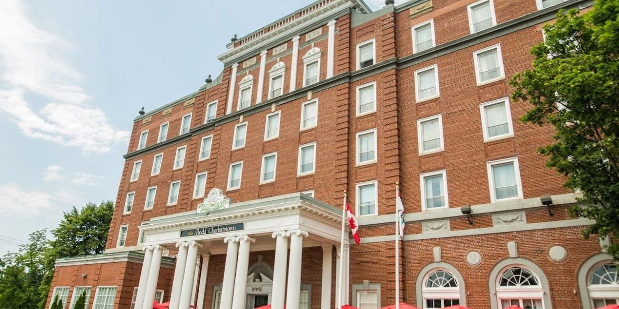 Historic red-brick building with white columns and Canadian flags.