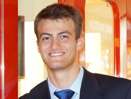 Young man in a suit smiling indoors.