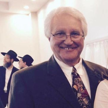 Smiling elderly man in suit and tie at a formal event.