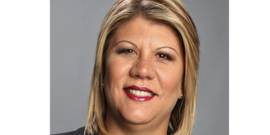 Professional headshot of a smiling woman with blonde hair against a gray background.