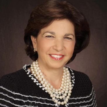 Professional portrait of a smiling woman with pearl necklace.