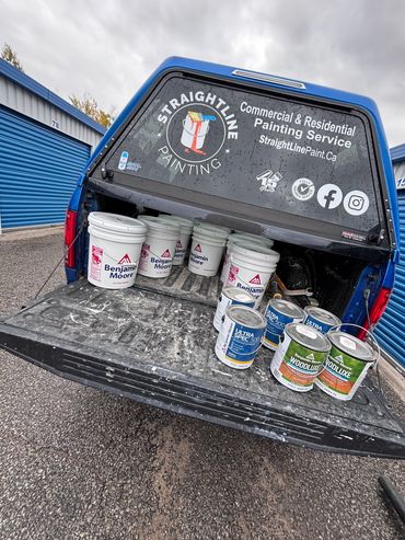 Truck bed loaded with paint buckets for a painting service business.