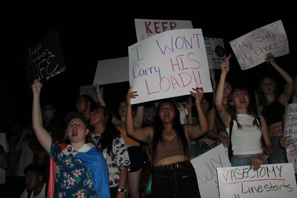 Protesters holding signs advocating for abortion rights at night.