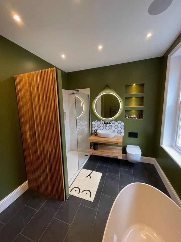 Modern bathroom with olive green walls, wooden accents, and geometric tiles.