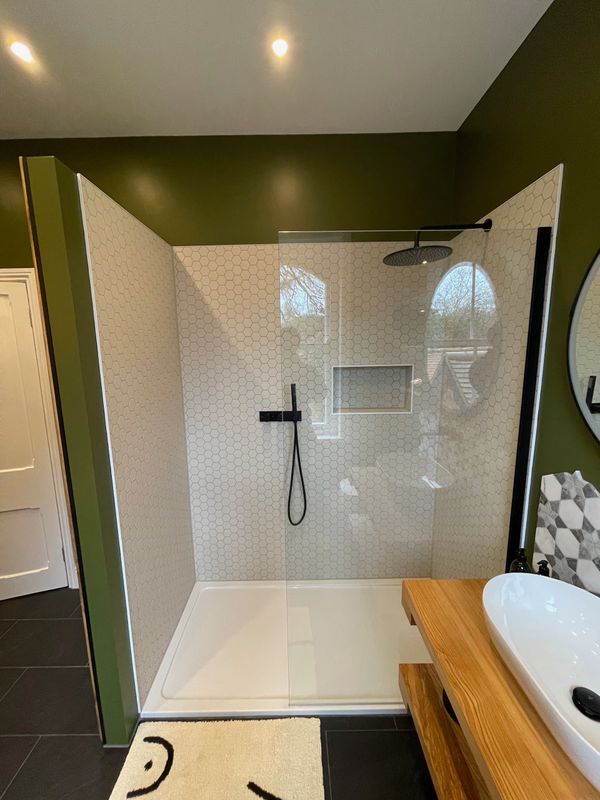 Modern bathroom shower with glass door and hexagonal tiles.