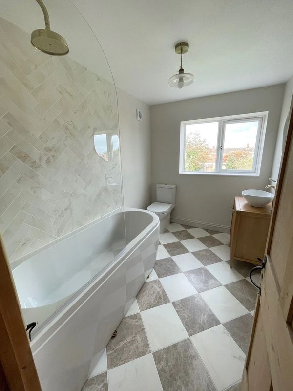 Bright modern bathroom with bathtub, toilet, and sink.