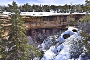Ancient cliff dwellings nestled in a snowy canyon landscape.