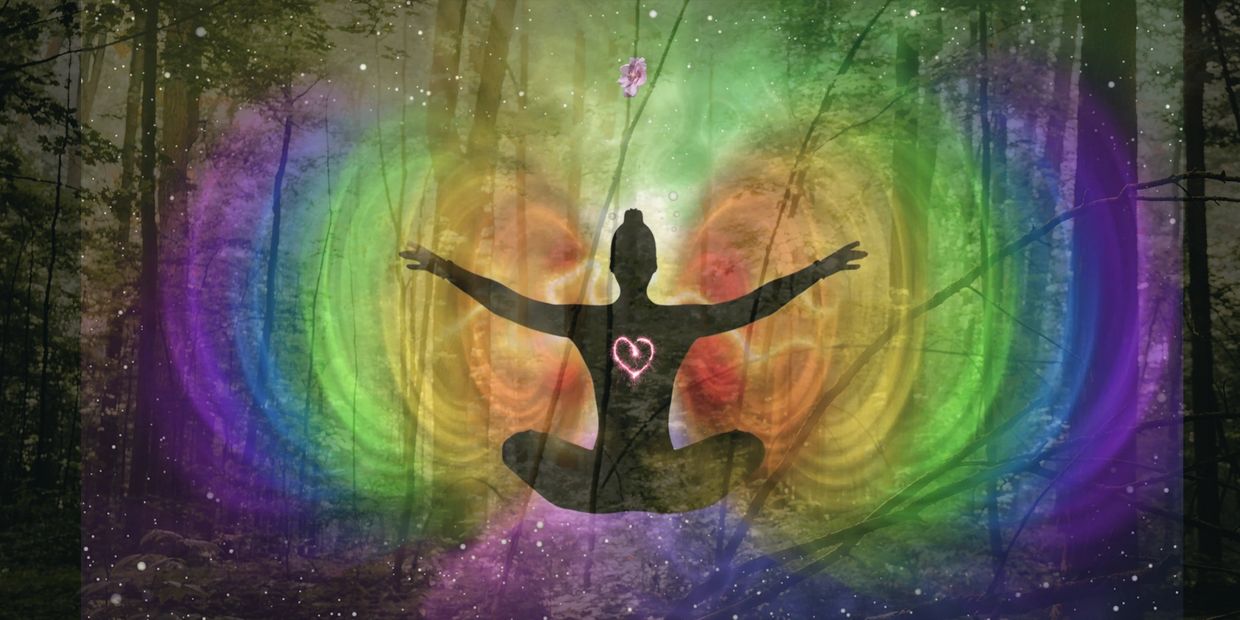 Silhouette meditating with colorful aura and heart glow in mystical forest.
