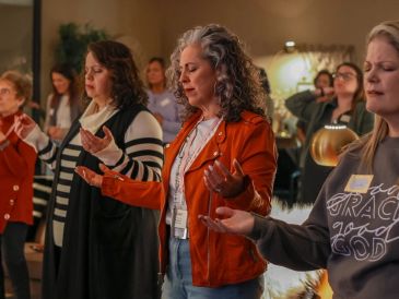 Women praying together in a group setting.