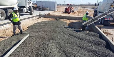 Workers pouring concrete at a construction site with cement trucks.