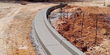 Freshly poured curved concrete curb on a construction site.