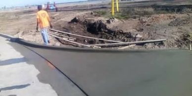 A man walks beside freshly poured concrete on a curved path.