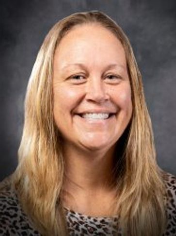 Smiling woman with long blonde hair against a dark background.