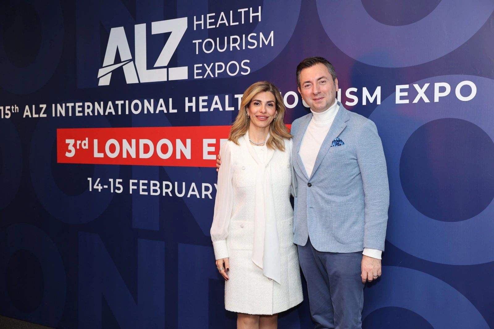 Two people posing at the ALZ Health Tourism Expo in London.