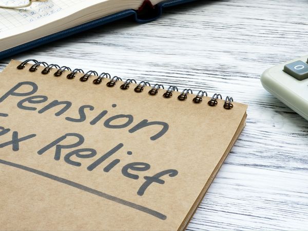 Notebook with 'Pension Tax Relief' written on a wooden desk.