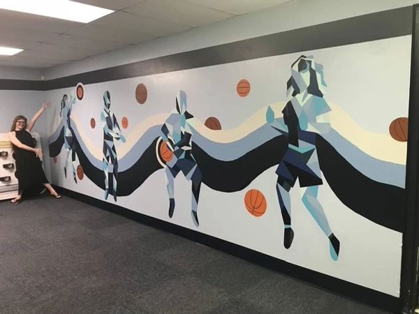 Geometric basketball mural on a wall with a woman posing.