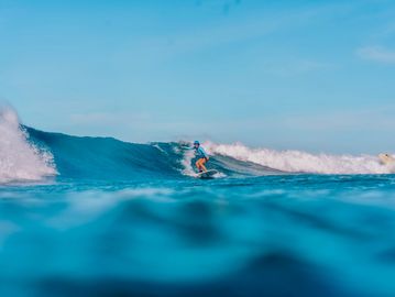 Surfer riding a wave on a bright sunny day.