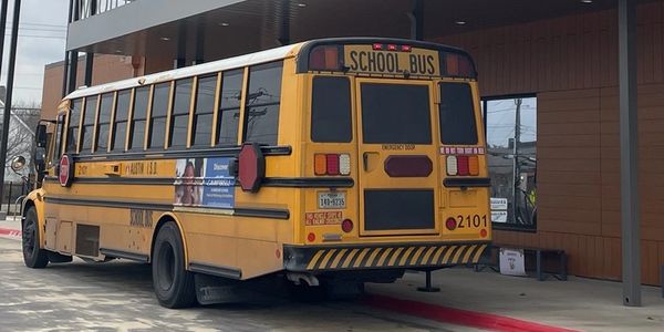 Yellow school bus parked near a building with a red curb.