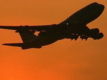Silhouetted cargo plane against an orange sky.