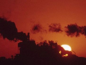 Silhouetted industrial plant emitting dark smoke.







